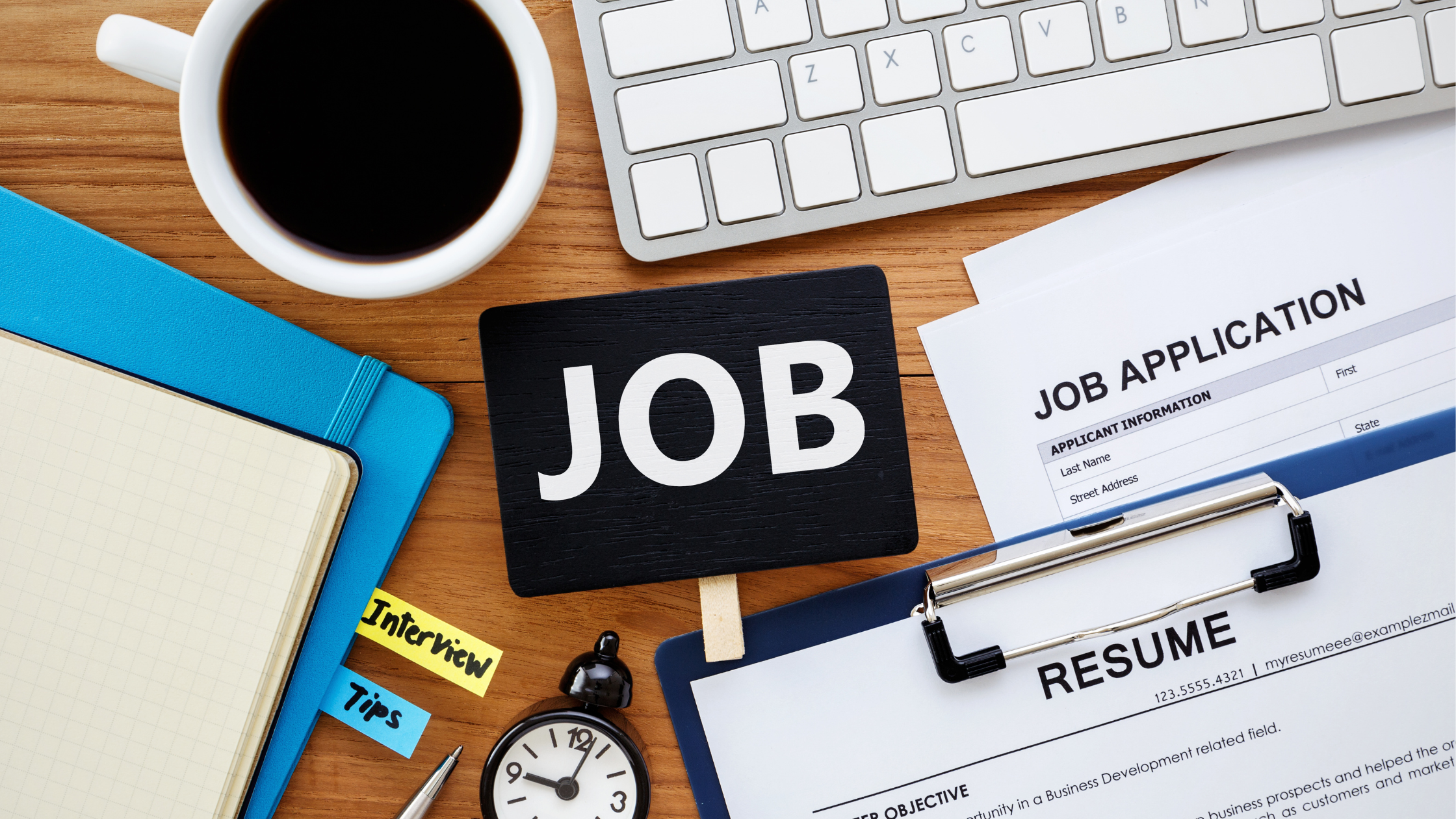 coffee cup the word job on a note white keyboard black clock ,folders resume and job application papers on brown desk